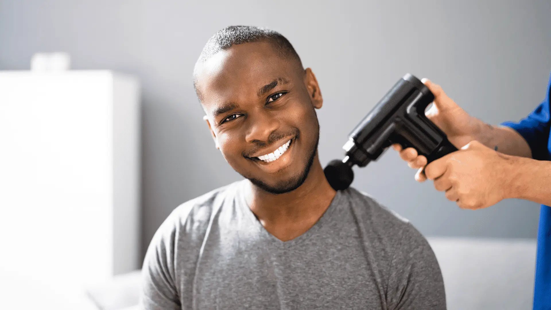 Man receiving massage gun treatment for neck pain using a massage gun image