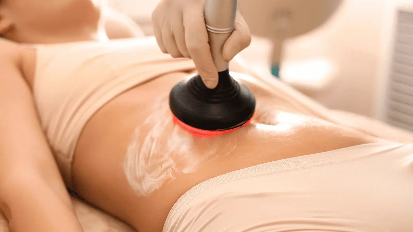 Cavitation treatment on the abdominal area demonstrating use of a massage gun on internal organs