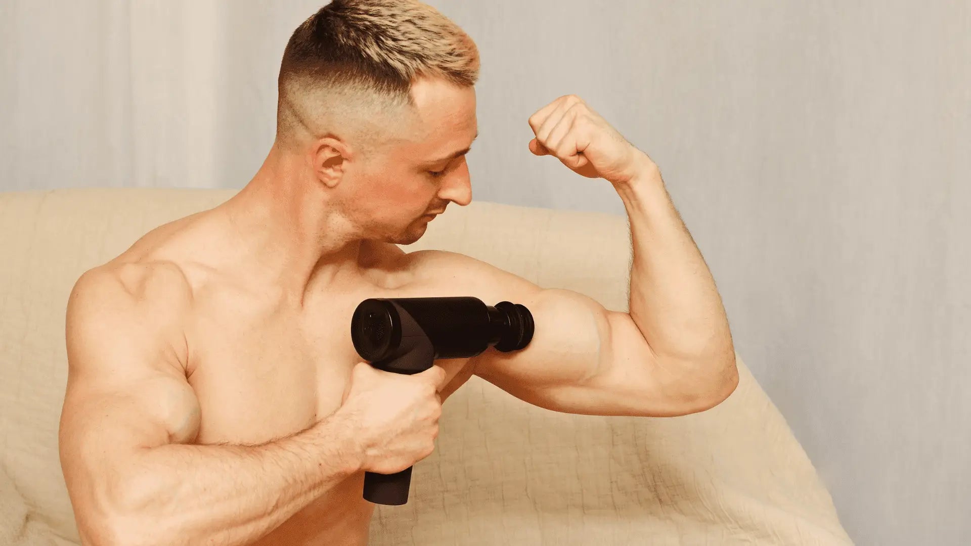Shirtless man using massage gun to enhance muscle growth and recovery