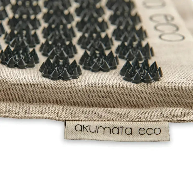 Black acupressure mat Akumata Eco with plastic spikes on beige mat
