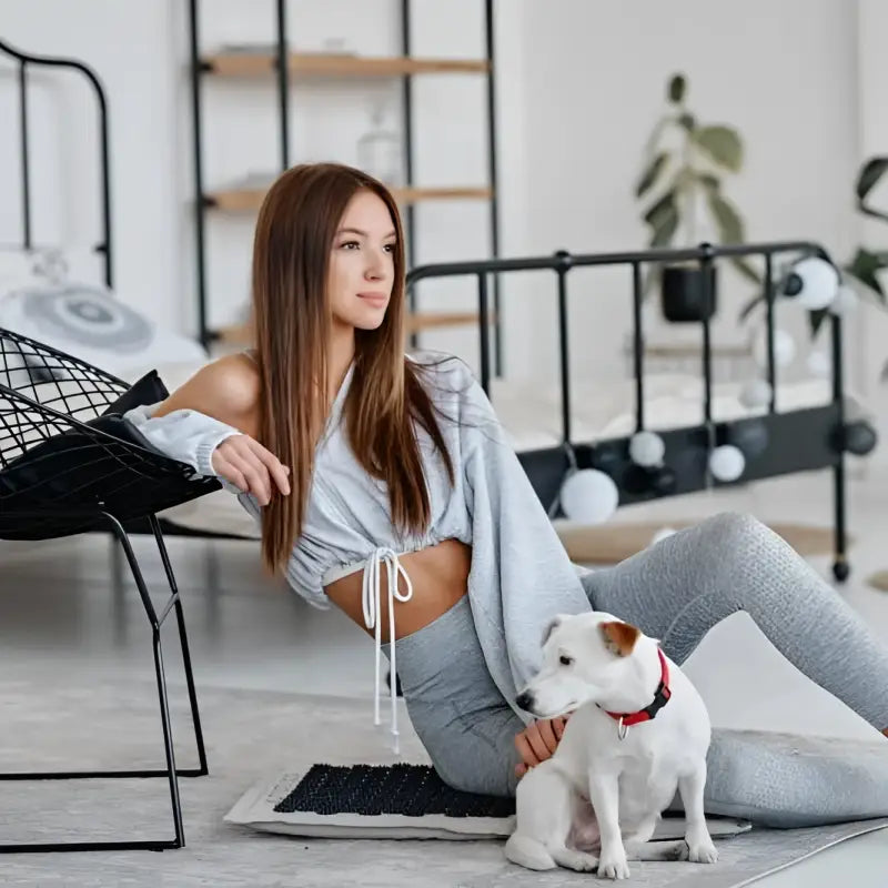 Woman with white dog beside black acupressure mat Akumata ECO