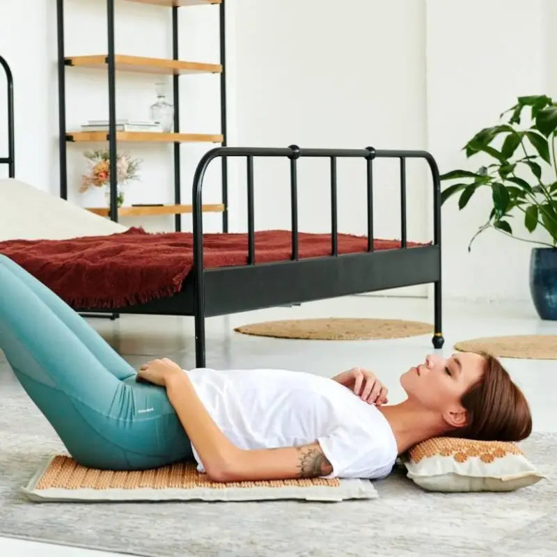 Woman relaxing on a brown acupressure mat with matching pillow for stress relief