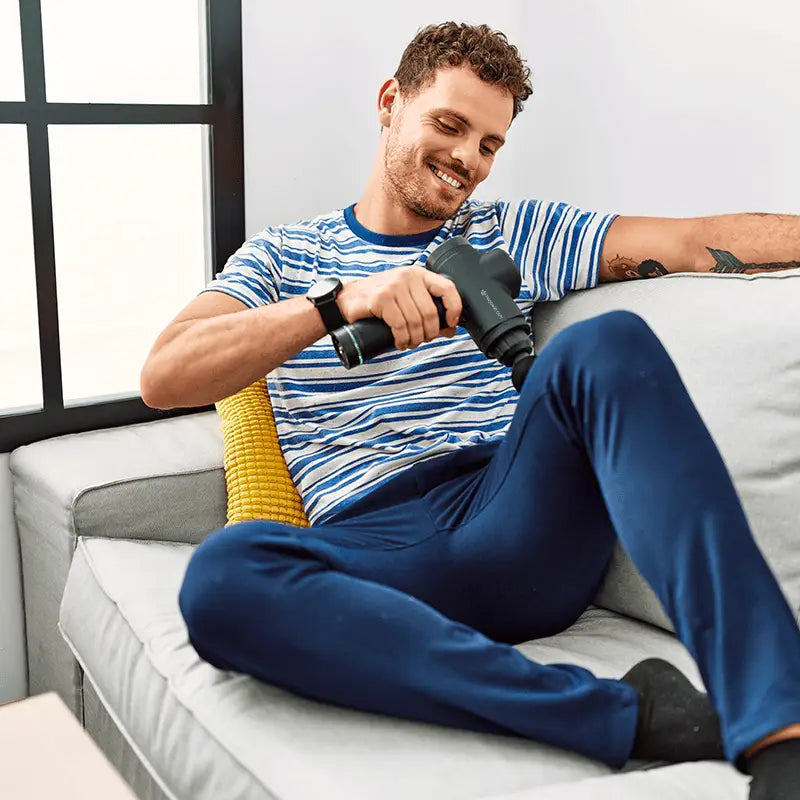 Man using percussion massage gun for muscle recovery and soothing sore muscles