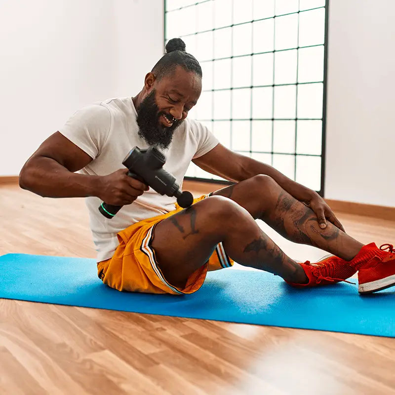 Man using percussion massage gun for muscle recovery and sore muscles relaxation