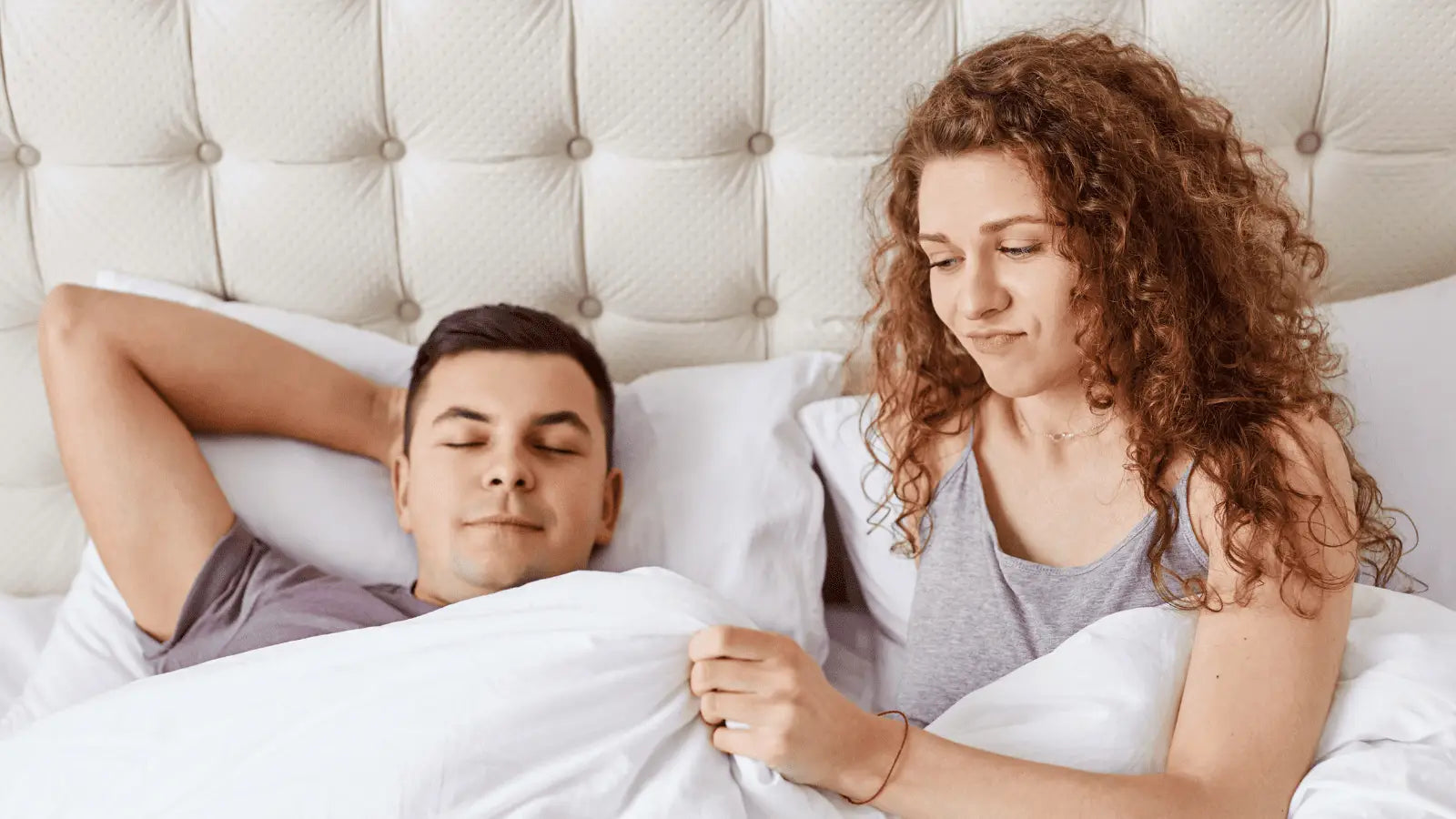 Couple in bed using a massage gun to promote pelvic floor health and shockwave therapy