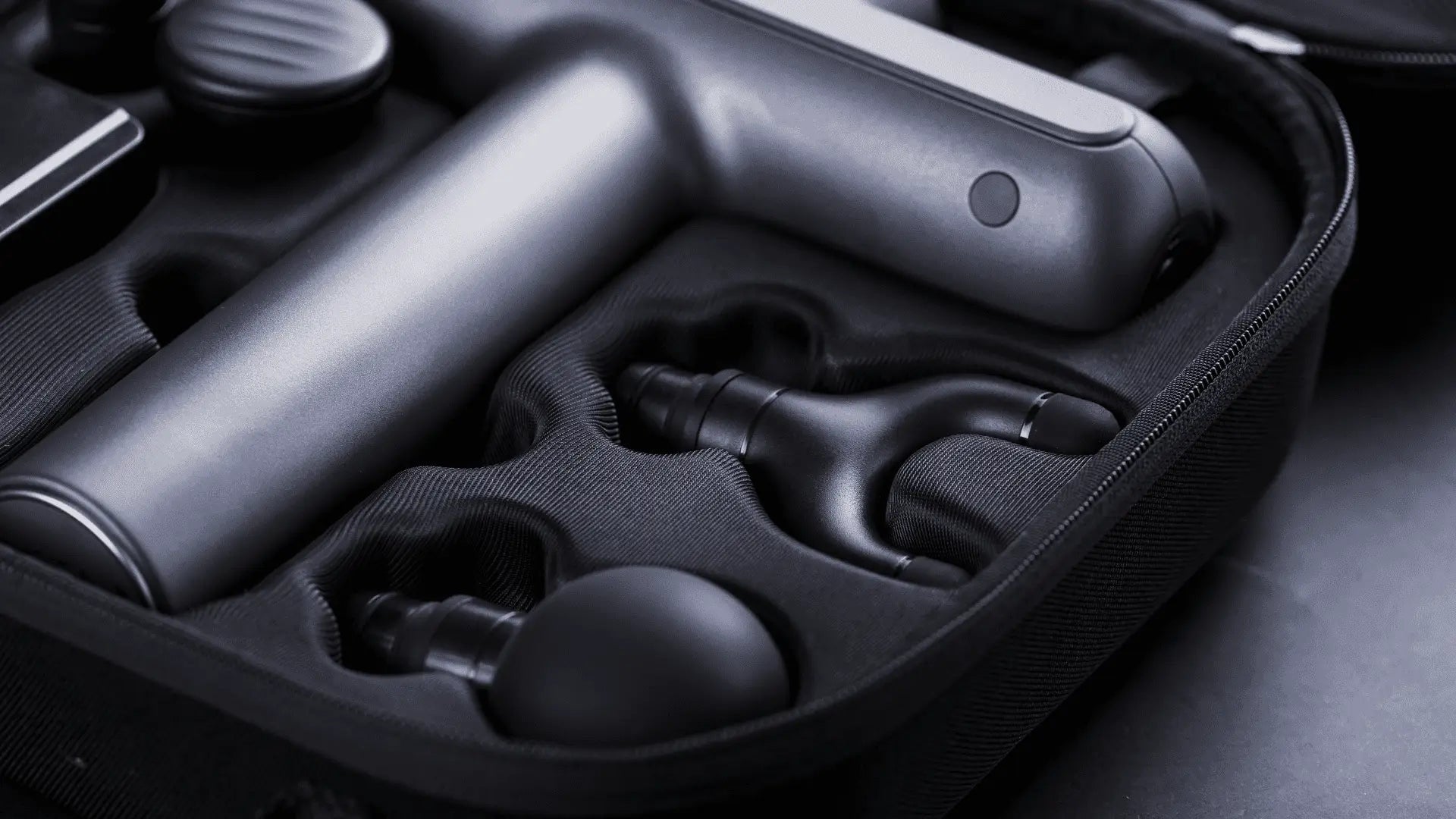 Gray massage gun with attachments in case for targeted muscle group relief using bullet head