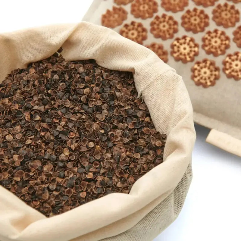 Burlap sack overflowing with dark brown buckwheat hulls for Brown Acupressure Mat Akumata ECO
