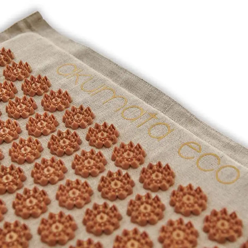 Light-colored brown acupressure mat with spiky lotus-shaped discs for relaxation and pain relief