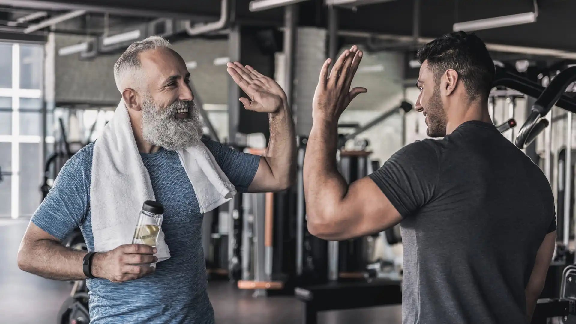 Two men high-fiving in a gym.